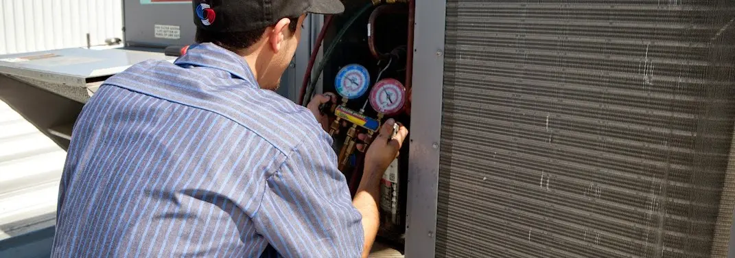 HVAC technician servicing a condenser unit in New Burlington